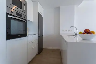 a white kitchen with a microwave and a bowl of fruit at Ocean Costa Ballena in Chipiona