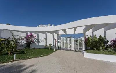 a white gate to a building with plants and flowers at Ocean Costa Ballena in Chipiona