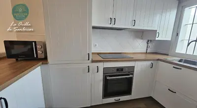 a kitchen with white cabinets and a microwave at La Orilla by Sanlucar Housing in Sanlúcar de Barrameda