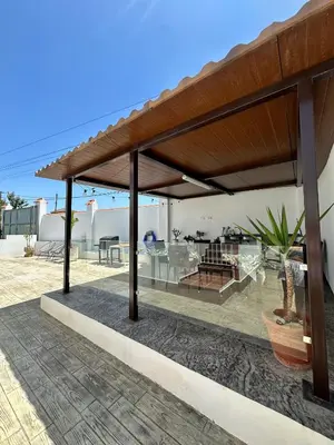 a pavilion with a table and chairs under a roof at Casa Adaro in Conil de la Frontera