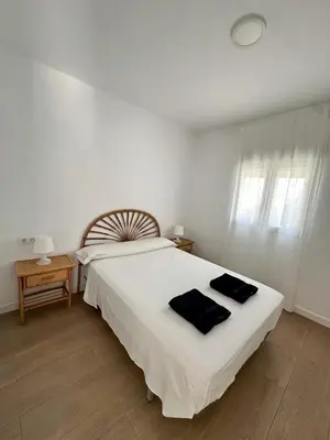 a bedroom with a large white bed with black towels on it at Casa Adaro in Conil de la Frontera