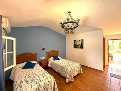 a bedroom with two beds and a chandelier at Villa La Alegría in Conil de la Frontera
