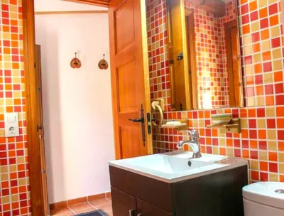 a bathroom with a sink and a mirror and a toilet at Villa La Alegría in Conil de la Frontera
