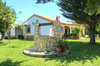 a house with a stone fountain in the yard at Villa La Alegría in Conil de la Frontera