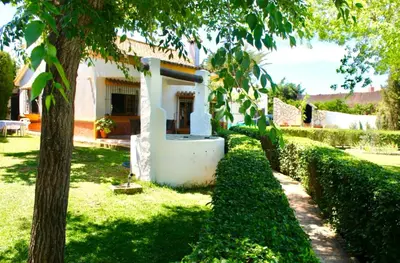a white house with a tree and bushes at Villa El Cortijo Andaluz in Cádiz