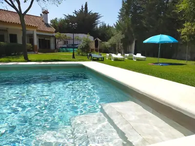 a swimming pool with an umbrella in a yard at Villa El Cortijo Andaluz in Cádiz