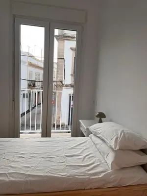 a white bed in a room with a window at Casa El Puerto in El Puerto de Santa María
