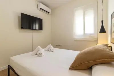 a white bedroom with a bed with towels on it at Allo Apartments Merced Duplex Centro 2 habitaciones - 2 Baños in Jerez de la Frontera
