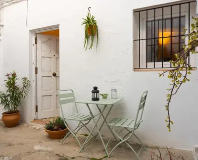a table and chairs next to a white wall at Casa Bombón in Medina Sidonia
