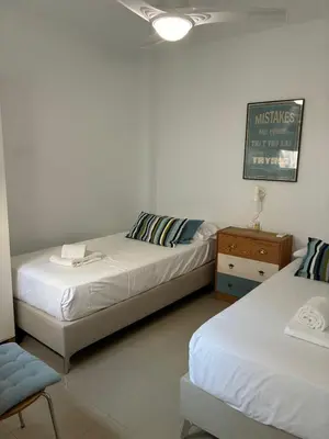 a bedroom with two beds and a chair and a table at Casa del Oratorio 1812 in Cádiz