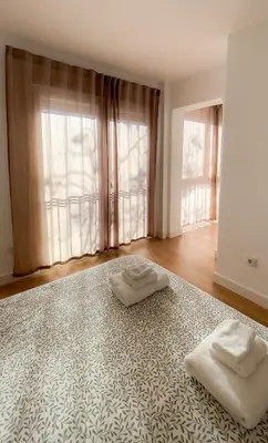 a hallway with white walls and wood floors and a chandelier at Casa Gadir in Sanlúcar de Barrameda