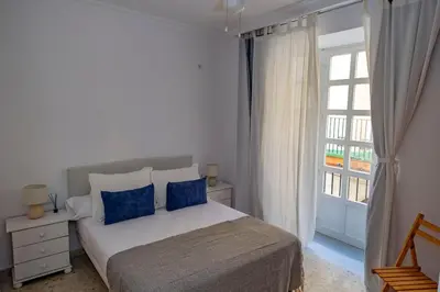 a bedroom with a bed with blue pillows and a window at GINVA - Apartamento en pleno centro 1 in El Puerto de Santa María