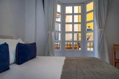 a bedroom with a bed and a large window at GINVA - Apartamento en pleno centro 1 in El Puerto de Santa María