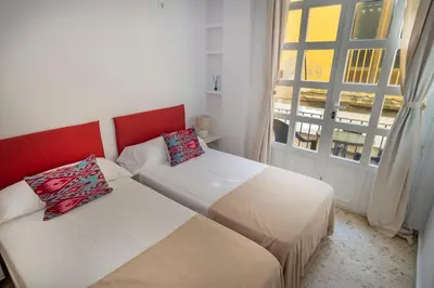 two beds in a small room with a window at GINVA - Apartamento en pleno centro 1 in El Puerto de Santa María