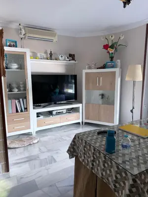 a living room with a tv and a table at Casa Coplas muy cerca de la playa in Sanlúcar de Barrameda