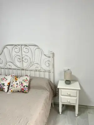 a white bed with a white nightstand next to a bed with a white bed at Encantador y céntrico piso con garaje in Sanlúcar de Barrameda