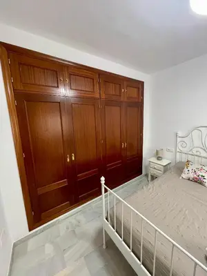 a bedroom with a bed and wooden cabinets at Encantador y céntrico piso con garaje in Sanlúcar de Barrameda