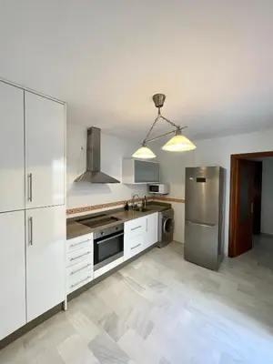 a kitchen with white cabinets and a stainless steel refrigerator at Encantador y céntrico piso con garaje in Sanlúcar de Barrameda