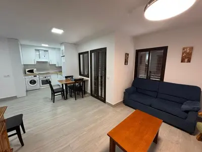 a living room with a blue couch and a table at Apartamento Completo en Chipiona in Chipiona