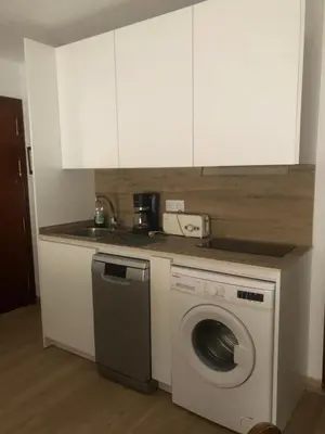 a kitchen with a washing machine and white cabinets at Puerto centro in El Puerto de Santa María