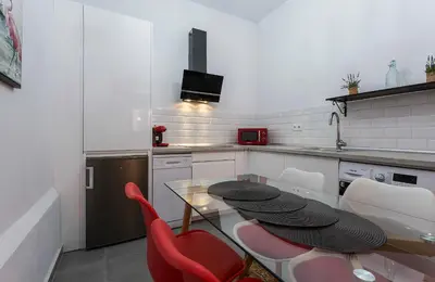 a kitchen with a glass table and red chairs at Duplex Los Corceles Casa Palacio in Jerez de la Frontera