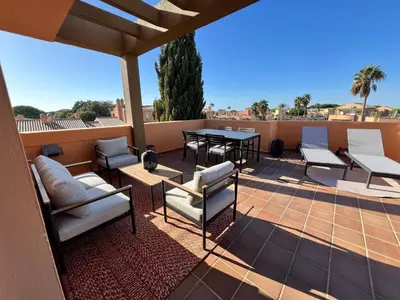 a patio with chairs and a table on a roof at Ático Jardín del Golf, Casa Alma in Chiclana de la Frontera