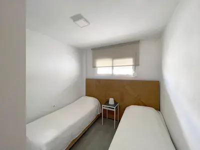 a small room with two beds and a window at Apartamento en primera linea de playa in Sanlúcar de Barrameda