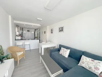 a living room with a blue couch and a kitchen at Apartamento en primera linea de playa in Sanlúcar de Barrameda