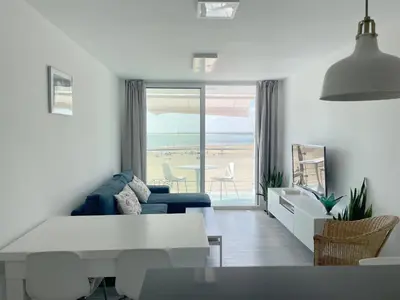 a living room with a blue couch and a view of the beach at Apartamento en primera linea de playa in Sanlúcar de Barrameda