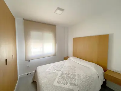 a bedroom with a white bed and a window at Apartamento en primera linea de playa in Sanlúcar de Barrameda