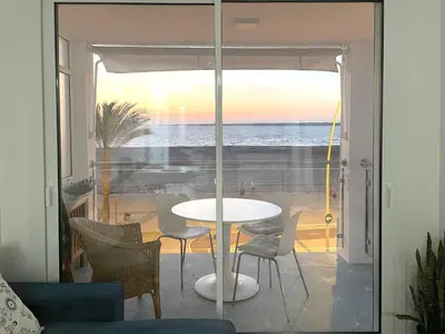 a table and chairs on a balcony with a view of the ocean at Apartamento en primera linea de playa in Sanlúcar de Barrameda
