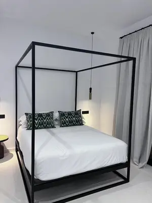 a black canopy bed with white sheets and pillows at Casa Chica Boutique in Sanlúcar de Barrameda