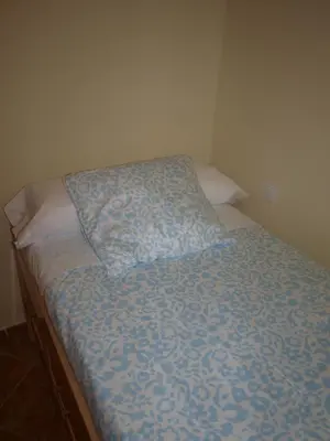 a bed with a blue comforter and a pillow at Corales 6 in El Puerto de Santa María
