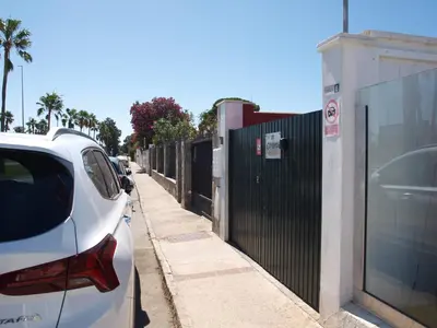 a white car parked on a sidewalk next to a fence at Corales 6 in El Puerto de Santa María