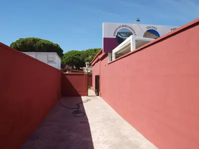 a red wall with a sidewalk next to a building at Corales 6 in El Puerto de Santa María