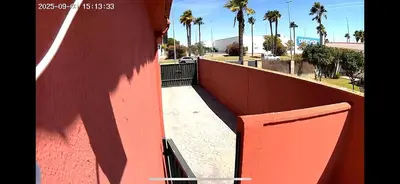 a red wall with a gate and palm trees at Corales 6 in El Puerto de Santa María