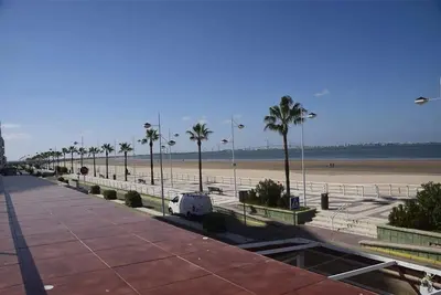 a white van parked next to a beach with palm trees at Corales 6 in El Puerto de Santa María