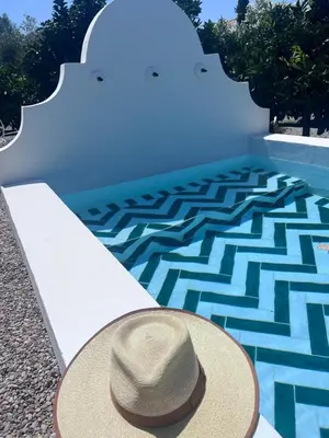a hat sitting on a bench next to a swimming pool at Casa Chica 2 in Sanlúcar de Barrameda