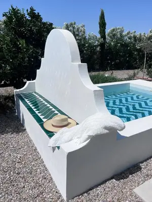 a hat sitting on a bench next to a swimming pool at Casa Chica 2 in Sanlúcar de Barrameda