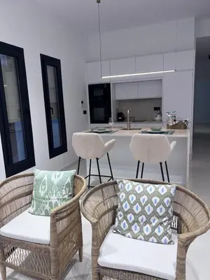 a kitchen with wicker chairs and a table and a kitchen at Casa Chica 2 in Sanlúcar de Barrameda