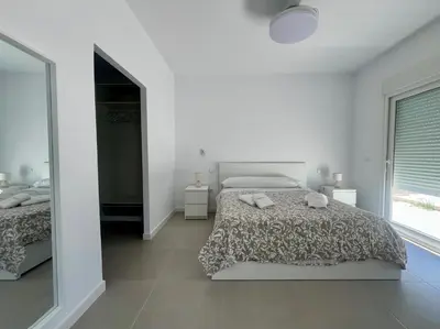 a white bedroom with two beds and a mirror at El Paraíso in Chiclana de la Frontera