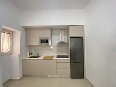 a kitchen with white cabinets and a black refrigerator at Sol Sherry in Jerez de la Frontera