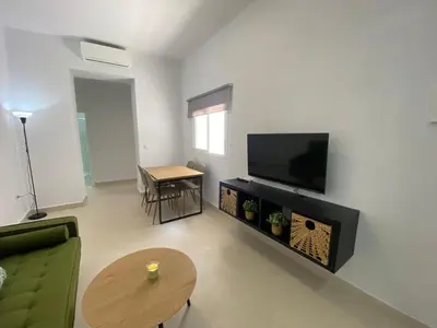 a living room with a couch and a tv and a table at Sol Sherry in Jerez de la Frontera