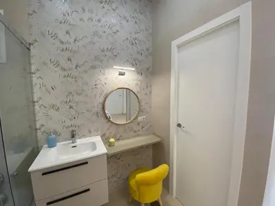 a bathroom with a sink and a mirror and a yellow chair at Sol Sherry in Jerez de la Frontera