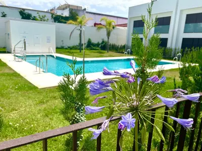 a fence with purple flowers next to a swimming pool at GATU Palacio de Rosa SOLO Familias in El Puerto de Santa María