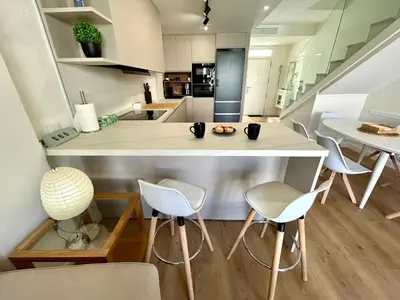 an open kitchen and dining room with white chairs at GATU Palacio de Rosa SOLO Familias in El Puerto de Santa María