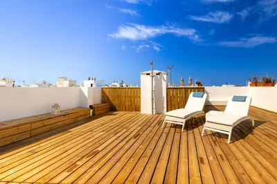 a balcony with two chairs and a wooden deck at Cadizz - Ático del Búho Surenyo - Terraza 100m2 privada in Cádiz