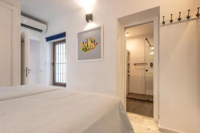 a white bedroom with a bed and a walk in shower at Cadizz - Ático del Búho Surenyo - Terraza 100m2 privada in Cádiz