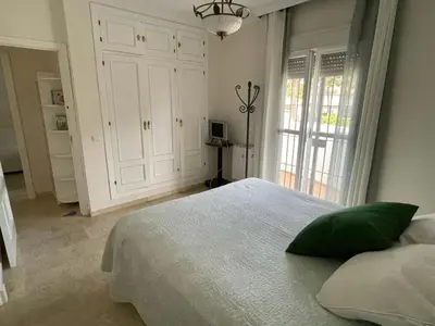 a bedroom with a white bed with a green pillow at Azafama Buena in Chiclana de la Frontera
