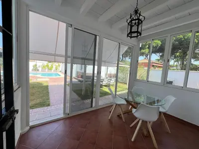 a dining room with a glass table and white chairs at Azafama Buena in Chiclana de la Frontera